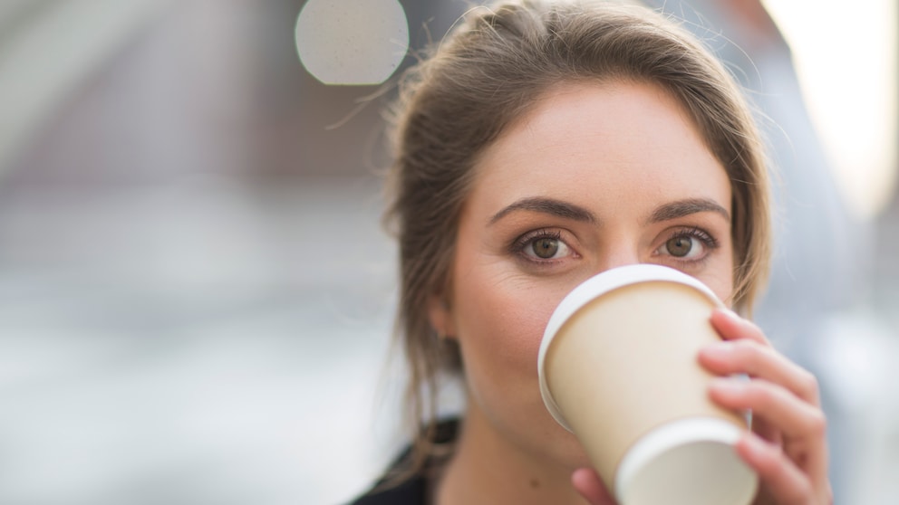 Junge Frau trinkt Kaffee aus To-Go-Becher