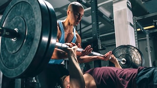 Exzentrisches Training. Mann unterstützt beim Bankdrücken