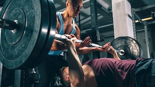 Exzentrisches Training. Mann unterstützt beim Bankdrücken