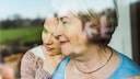 Alzheimer-Medikament Donanemab macht Hoffnung: Seniorin schaut aus dem Fenster, umarmt von jüngerer Frau