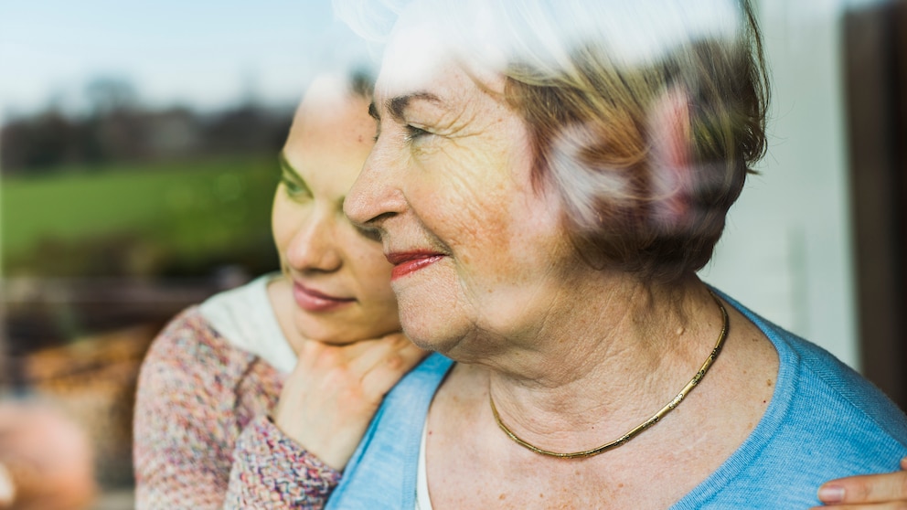 Alzheimer-Medikament Donanemab macht Hoffnung: Seniorin schaut aus dem Fenster, umarmt von jüngerer Frau