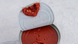 Opened pull open top tomato paste can on decorative surface. High point of view. Selective focus.