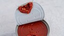 Opened pull open top tomato paste can on decorative surface. High point of view. Selective focus.