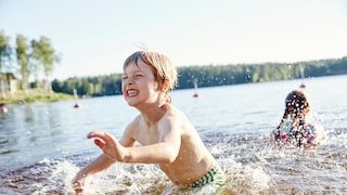 Gefahren beim Baden: Kinder spielen im Wasser am Ufer eines Sees