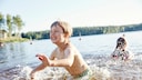 Gefahren beim Baden: Kinder spielen im Wasser am Ufer eines Sees