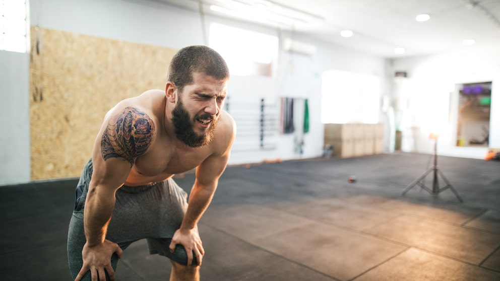 Muskulöser Sportler stützt sich erschöpft ab