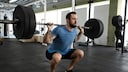 besseres Muskelwachstum: Mann macht Squats mit Langhantel