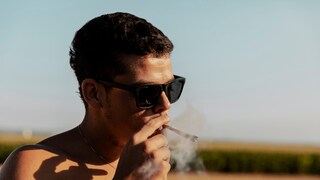 Marihuana Hoden: Ein junger Mann raucht einen Joint