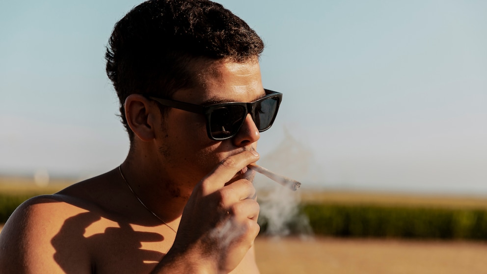Marihuana Hoden: Ein junger Mann raucht einen Joint