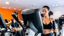 fettverbrennungszone abnehmen: Zwei Frauen im Gym auf einem Crosstrainer