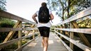 Rucking: Junger Mann joggt mit Rucksack