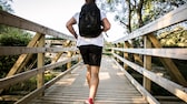 Rucking: Junger Mann joggt mit Rucksack