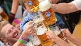 Wiesn-Besuch abtrainieren: Menschen stoßen mit Bierkrügen an