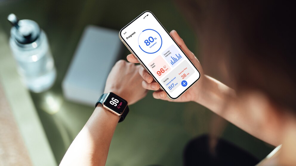 Süchtig durch Fitnesstracker: Junge Frau blickt auf Smartwatch