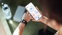 Süchtig durch Fitnesstracker: Junge Frau blickt auf Smartwatch