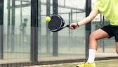 Sportler mit gelbem Shirt und Schuhen spielt Padel.