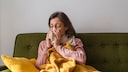 Long Cold oder chronische Erkältung? Frau putzt sich die Nase