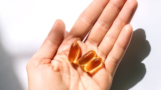 Person hält Omega-3-Kapseln in der Hand.