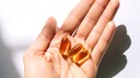 Person hält Omega-3-Kapseln in der Hand.