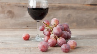 Glas Rotwein und Weintrauben.