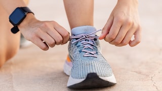 Jemand bindet sich Laufschuhe zu