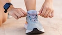 Jemand bindet sich Laufschuhe zu