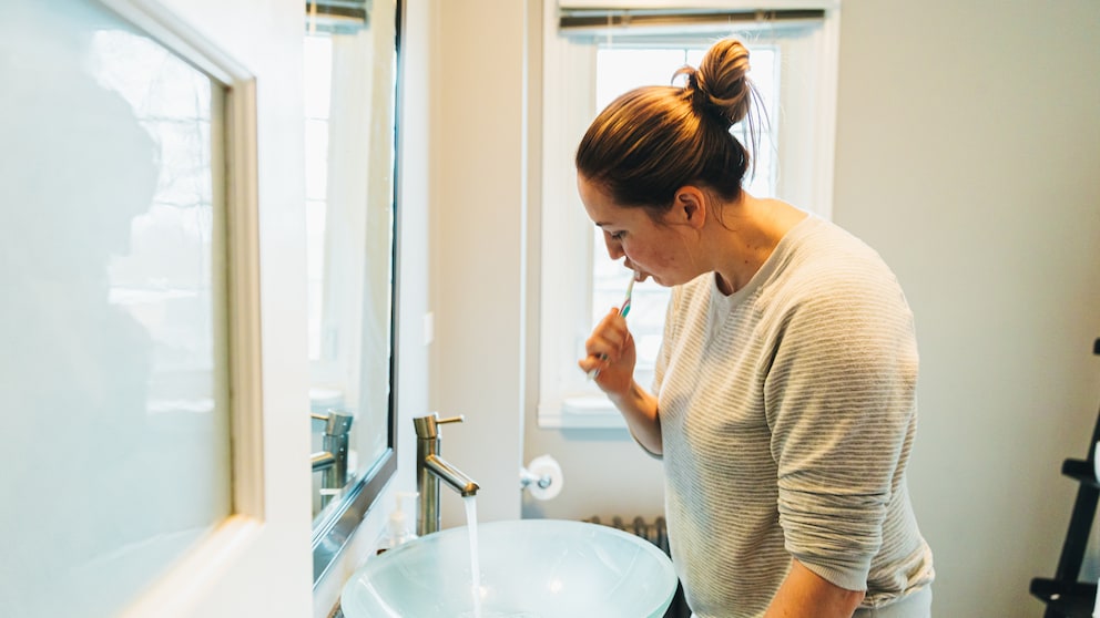 Frau beim Zähneputzen – sollte man danach den Mund ausspülen?