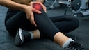 Frau fasst sich ans Knie