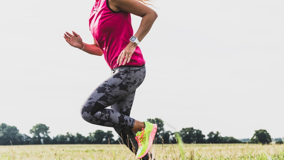 Frau mit Laufuhr joggt im Freien