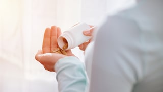 Tabletten aus der Dose auf die Hand