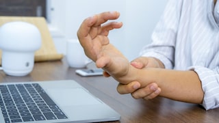 Businesswoman holding her wrist pain from using the computer.