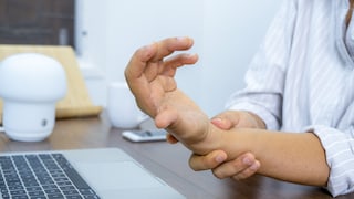 Businesswoman holding her wrist pain from using the computer.