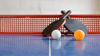Tischtennisschläger und Bälle auf einer Platte
