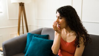 Eine Frau untersucht, ob sie an Mundgeruch leidet.