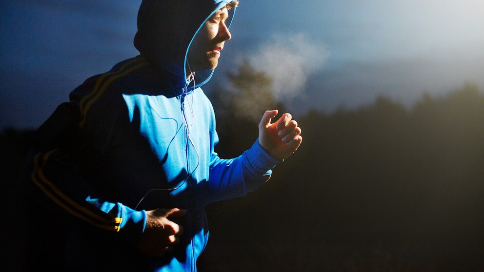 Sport vor dem Schlafen: Mann im Hoodie läuft am Abend