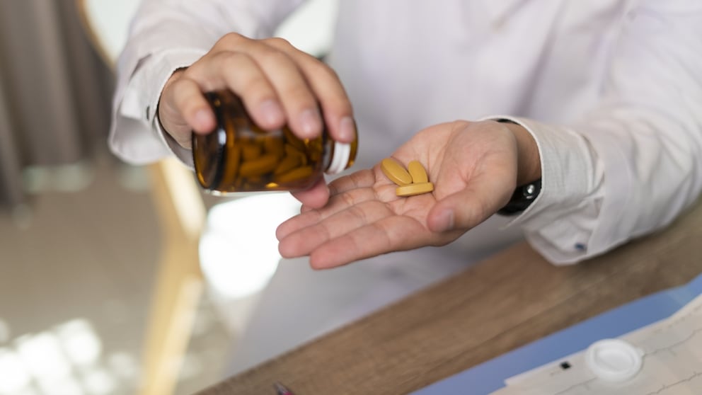 Mann nimmt Supplements beziehungsweise Nahrungsergänzungsmittel aus Flasche