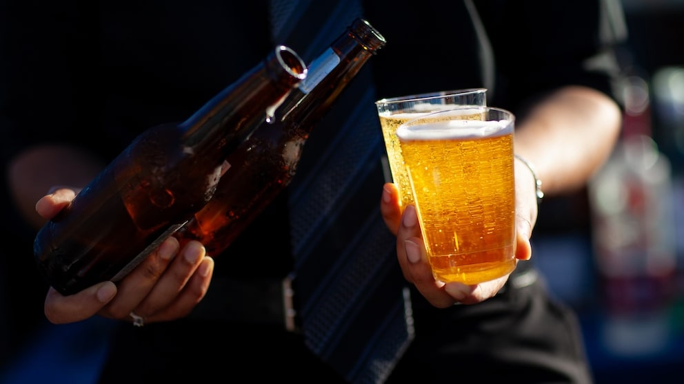 Mann hält zwei Becher Bier