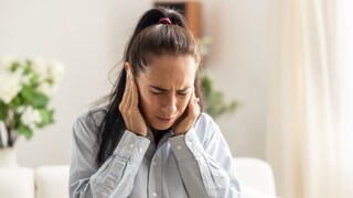 Hörprobleme bei Erkältung: Eine Frau hält sich ans Ohr.