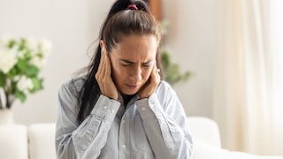 Hörprobleme bei Erkältung: Eine Frau hält sich ans Ohr.