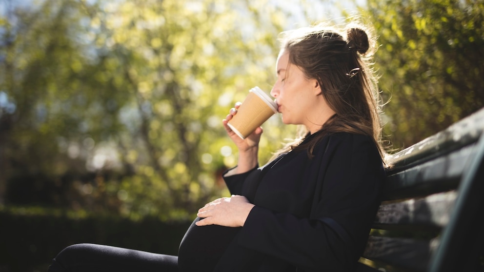 Eine schwangere Frau trinkt Kaffee.