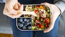 Gesunde Snacks in einer Dose mit Beere, Quinoa etc.