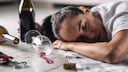 Drunk woman fell asleep on the floor at home with glass of red wine spilled next to her.