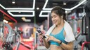 Frau im Fitness-Studio mit Handtuch und Smartphone