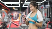 Frau im Fitness-Studio mit Handtuch und Smartphone