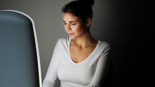 Frau sitzt vor Tageslichtlampe