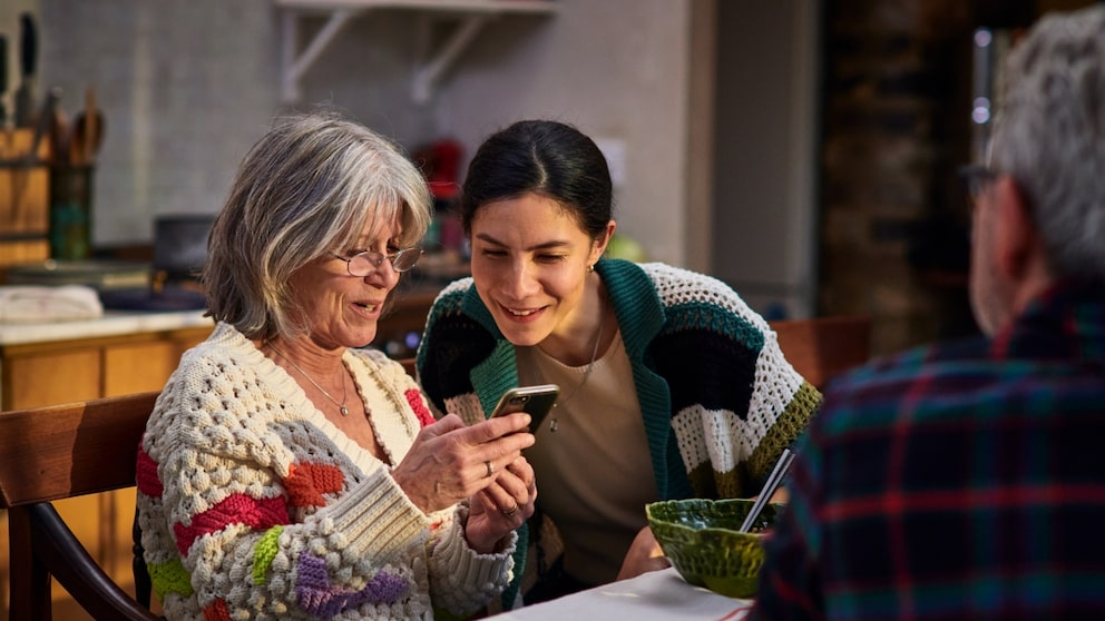 Menschen Ü50 mit jüngerer Frau vor dem Smartphone