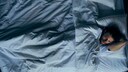 Mann liegt gr&uuml;belnd im Bett