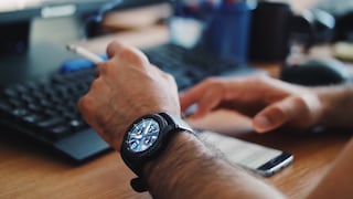 Ein Mann mit einer Smartwatch raucht am Schreibtisch