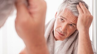 Ein Mann fasst sich durch die grauen Haare