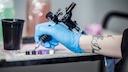 Augen t&auml;towieren lassen: Hand h&auml;lt Tattoo-Nadel